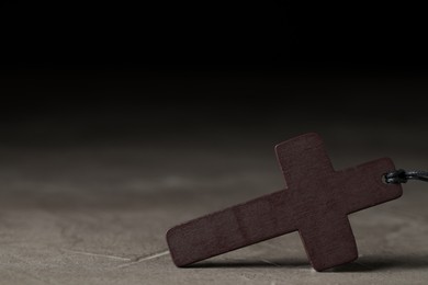 Wooden Christian cross on grey table, closeup. Space for text
