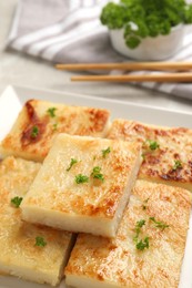 Delicious turnip cake with parsley served on light table, closeup