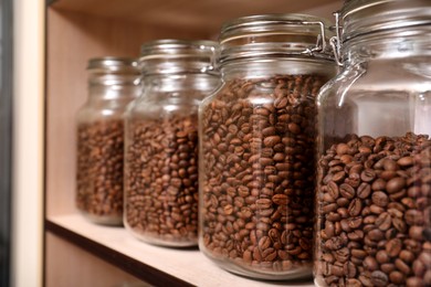 Glass jars with coffee beans on rack, space for text