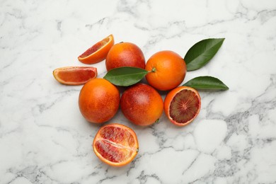 Many ripe sicilian oranges and leaves on white marble table, flat lay