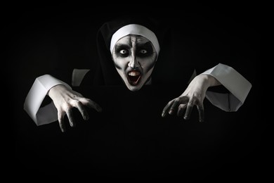 Scary devilish nun frightening on black background. Halloween party look