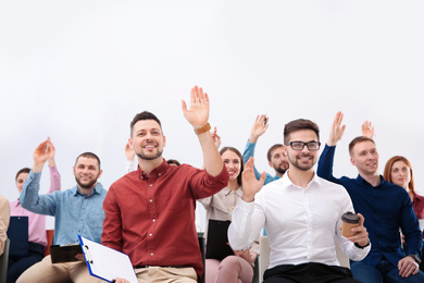 People raising hands to ask questions at business training on white background