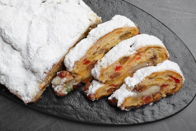 Traditional Christmas Stollen with icing sugar on black table, top view