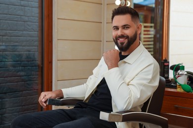 Photo of Young man with fresh haircut and groomed beard in barbershop