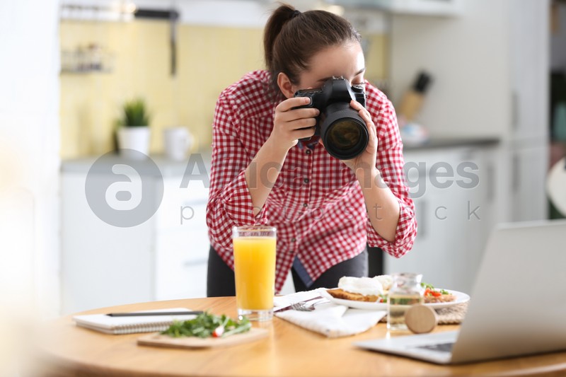 Food blogger taking photo of her lunch at wooden table indoors