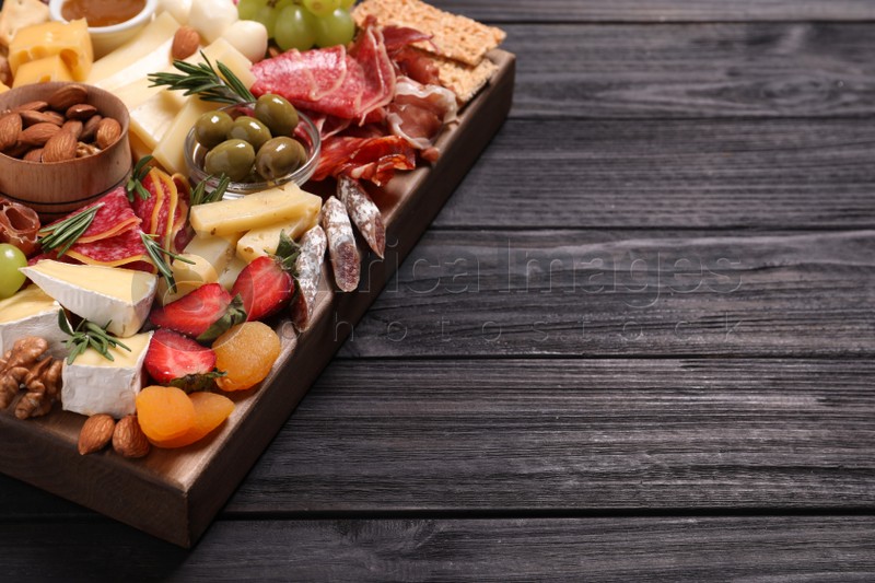Assorted appetizers served on black wooden table. Space for text