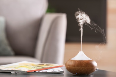 Aroma oil diffuser lamp on table against blurred background