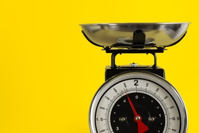 Retro mechanical kitchen scale on yellow background, closeup. Space for text