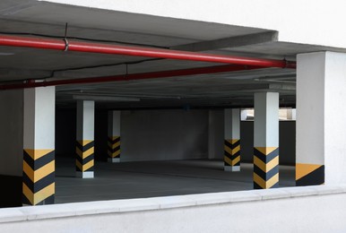 Empty car parking garage with warning stripes on columns