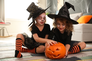 Cute little girls with pumpkin head jack lantern wearing Halloween costumes at home