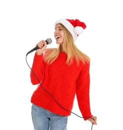 Happy woman in Santa Claus hat singing with microphone on white background. Christmas music