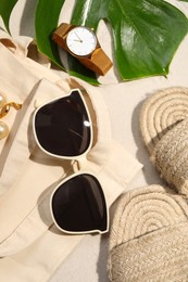 Flat lay composition with stylish sunglasses and other fashionable accessories on sand