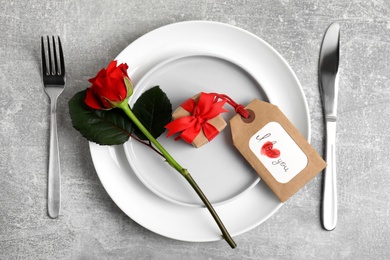 Beautiful table setting for romantic dinner on light grey background, flat lay. Valentine's day celebration