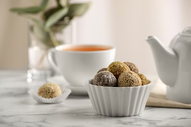 Photo of Different delicious vegan candy balls on white marble table indoors