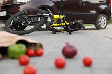 Scattered vegetables and fallen bicycle after car accident on street