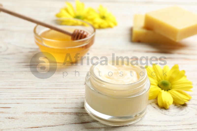 Cream with natural beeswax component on white wooden table, closeup view