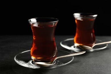 Photo of Glasses with traditional Turkish tea on black table