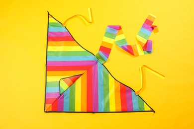 Bright rainbow kite on yellow background, top view