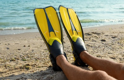Man in flippers near sea on beach, closeup