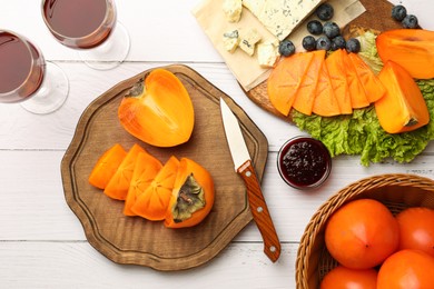 Photo of Delicious persimmon, blue cheese, blueberries and jam served on white wooden table, flat lay