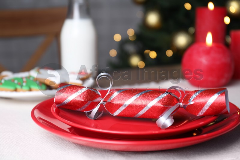 Red plate with Christmas cracker on table, closeup