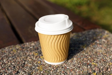 Paper cup on parapet outdoors, closeup. Coffee to go