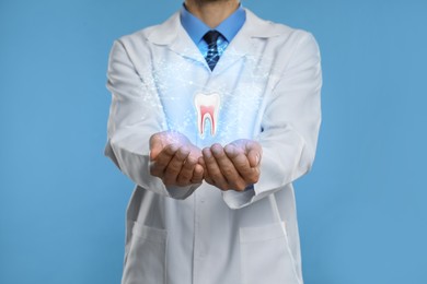 Dentist showing virtual model of tooth on light blue background, closeup