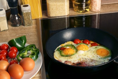 Photo of Cooking eggs with bacon, tomatoes and pepper in frying pan