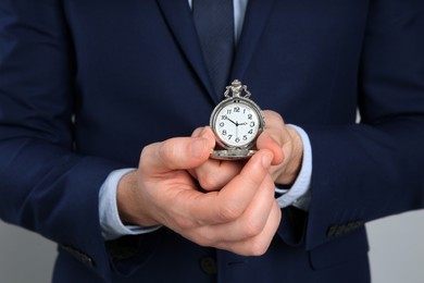 Businessman holding pocket watch, closeup. Time management