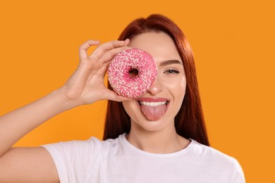 Photo of Happy woman with red dyed hair and donut on orange background