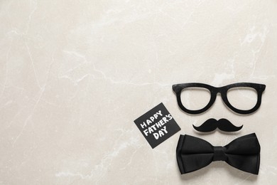 Photo of Card with phrase Happy Father's Day, paper glasses, mustache and bow tie on light background, flat lay. Space for text