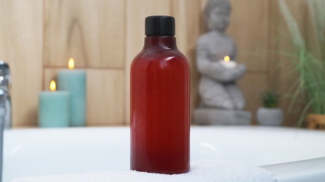 Red bottle of bubble bath on tub indoors