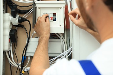 Photo of Electrician switching off circuit breakers in fuse box, closeup
