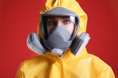 Woman wearing chemical protective suit on red background, closeup. Virus research
