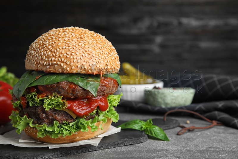 Delicious burger with meat cutlets on grey table. Space for text