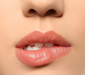 Beautiful young woman biting lip on grey background, closeup