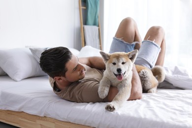 Image of Happy man with his cute Akita Inu puppy at home