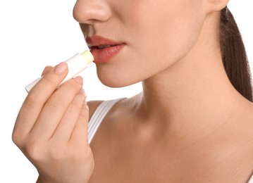 Young woman applying lip balm on white background, closeup