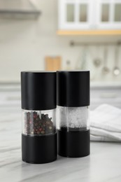Salt and pepper mills with napkin on white marble table in kitchen