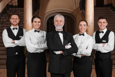 Photo of Group of young trainees with teacher in hotel. Professional butler courses
