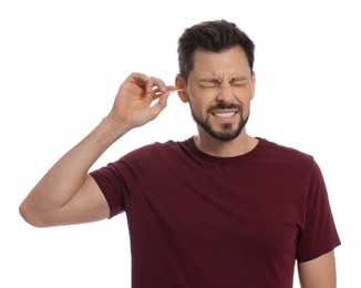 Man cleaning ears and suffering from pain on white background