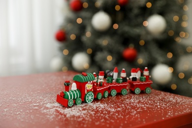 Bright toy train on table in room with Christmas tree