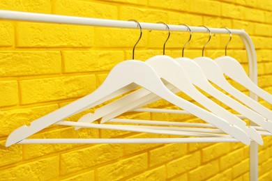 Wardrobe rack with many hangers near yellow brick wall