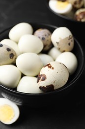 Photo of Unpeeled and peeled hard boiled quail eggs on black table, closeup