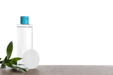 Micellar water in bottle and cotton pads on wooden table against white background. Space for text