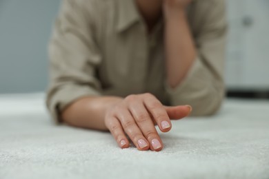 Photo of Woman touching soft white carpet indoors, closeup
