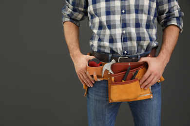 Photo of Carpenter with tool belt on dark background, closeup