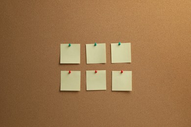 Beige paper notes pinned to cork board