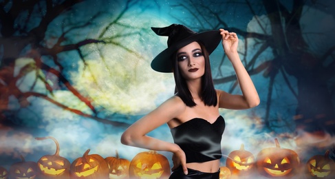 Young girl dressed as witch surrounded by spooky pumpkin heads in misty forest on full moon night. Halloween fantasy