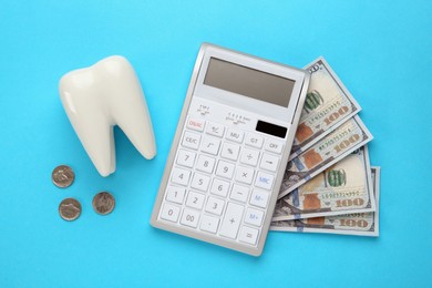 Ceramic model of tooth, money and calculator on light blue background, flat lay. Expensive treatment